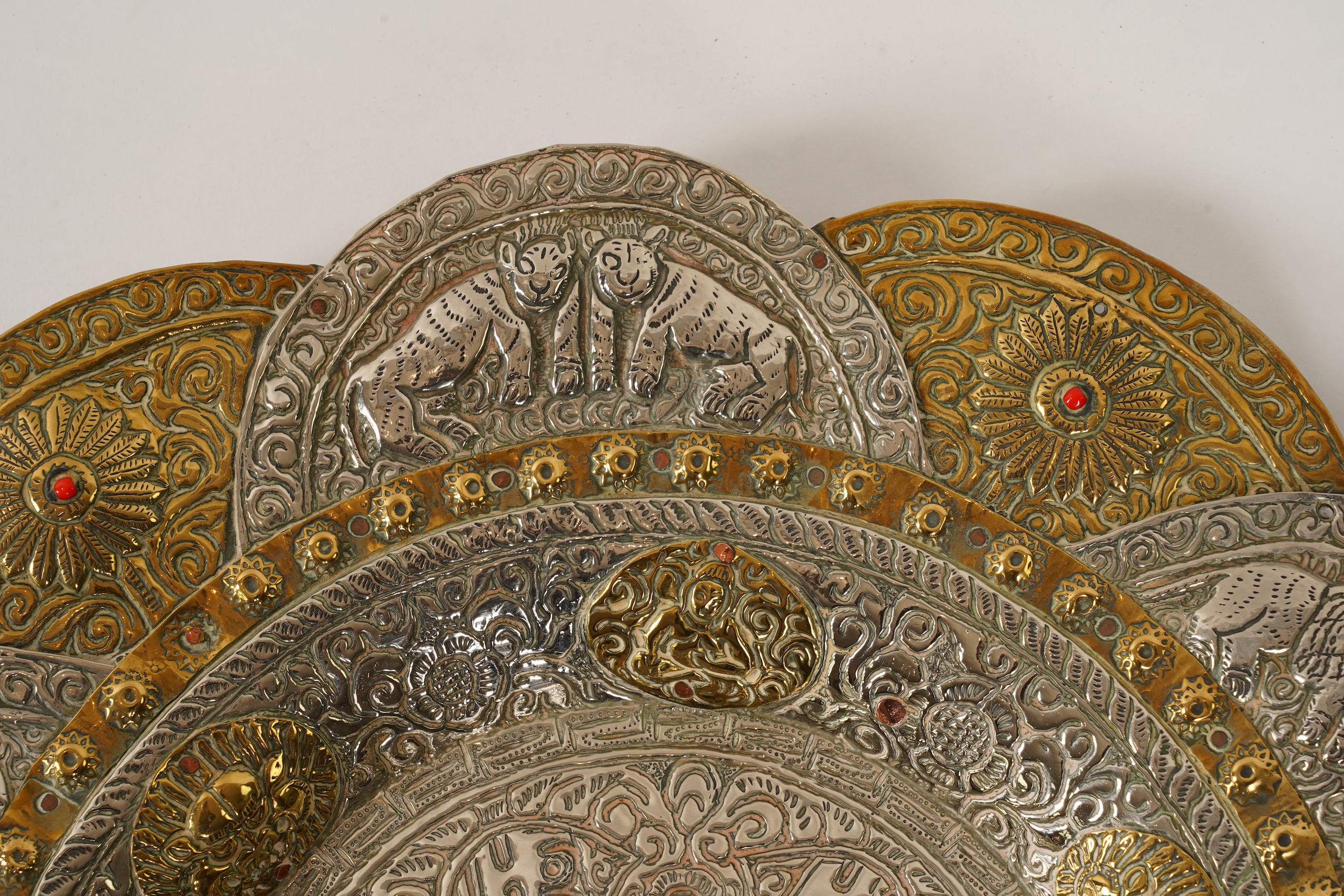 A graduated set of three Nepalese repoussé white metal and brass chargers, first half 20th century